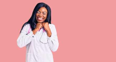Young african american woman wearing doctor stethoscope laughing nervous and excited with hands on...