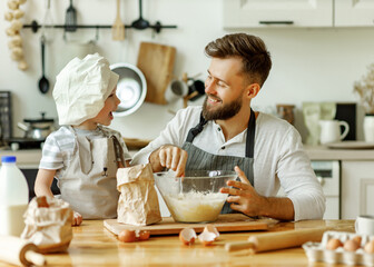 Happy man with kid preparing dough at home.