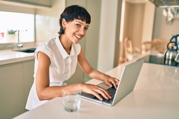 Beautiful brunette woman with short hair at home using computer laptop