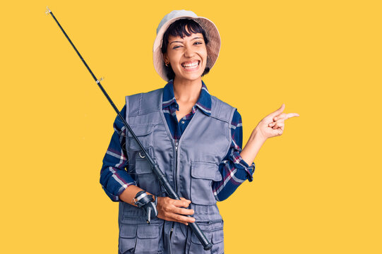 Young brunette woman with short hair wearing fisherman equipment smiling happy pointing with hand and finger to the side
