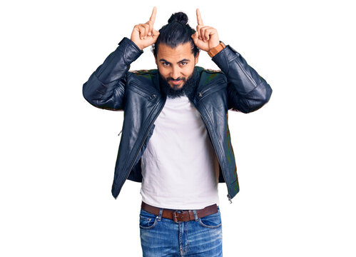 Young arab man wearing casual leather jacket doing funny gesture with finger over head as bull horns