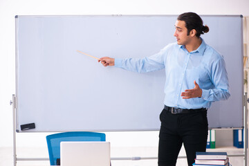 Young handsome teacher in front of whiteboard - Powered by Adobe