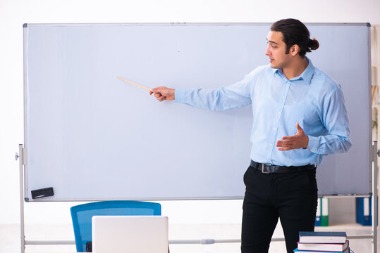 Young handsome teacher in front of whiteboard