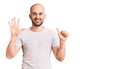 Young handsome man wearing casual t shirt showing and pointing up with fingers number six while smiling confident and happy.