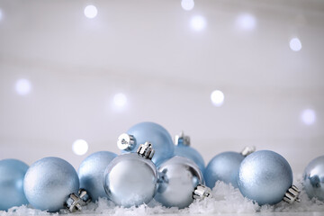 Beautiful Christmas balls on snow against blurred festive lights. Space for text
