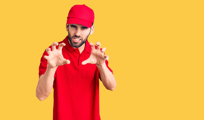 Young handsome man with beard wearing delivery uniform smiling funny doing claw gesture as cat,...