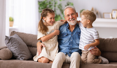 Grandfather hugging grandchildren on sofa