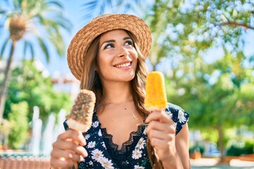 Young hispanic woman on vacation eating ice cream at the park.