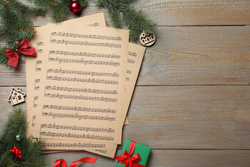 Flat lay with Christmas music sheets on wooden background, space for text