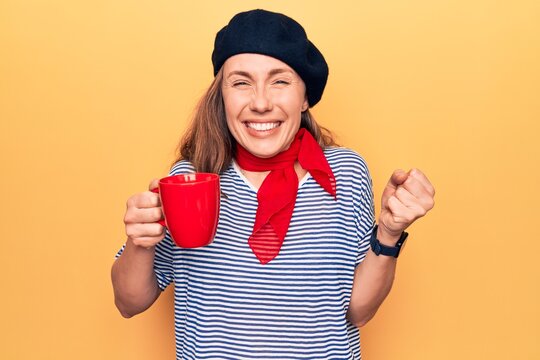 Young beautiful blonde woman wearing fashion beret drinking a cup of coffee screaming proud, celebrating victory and success very excited with raised arm
