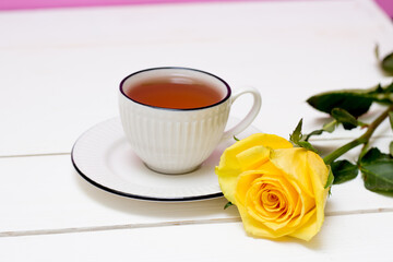 Fototapeta na wymiar A cup of tea and oatmeal cookies. Yellow rose. Breakfast. Tea drinking. White wood background and pink wall.
