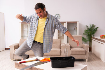 Young male carpenter repairing furniture at home
