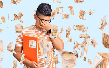 Little boy kid holding book wearing glasses tired rubbing nose and eyes feeling fatigue and...