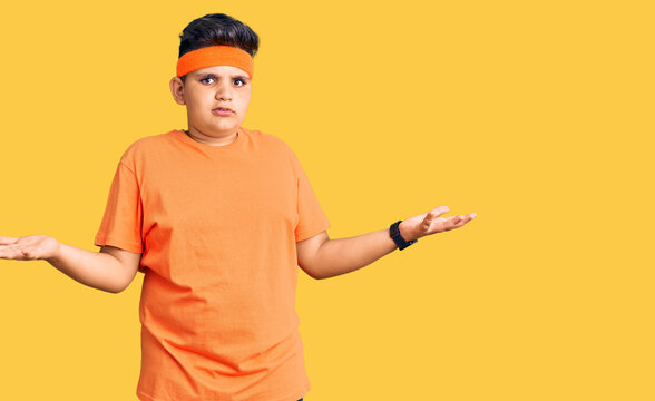 Little boy kid wearing sportswear clueless and confused with open arms, no idea concept.