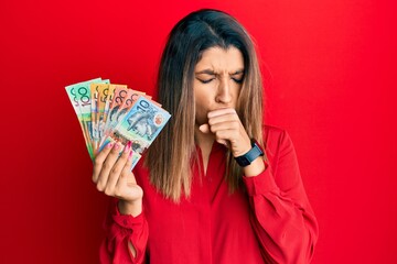 Beautiful brunette woman holding australian dollars feeling unwell and coughing as symptom for cold or bronchitis. health care concept.