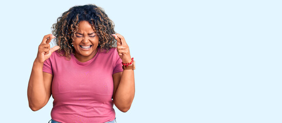 Young african american plus size woman wearing casual clothes gesturing finger crossed smiling with hope and eyes closed. luck and superstitious concept.