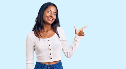 Young indian girl wearing casual clothes with a big smile on face, pointing with hand and finger to...