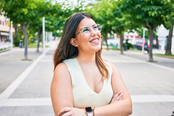 Young beautiful woman smiling happy with arms crossed. Standing with smile on face looking to the side walking at town street.