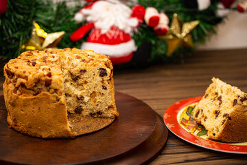 Fototapeta na wymiar Fruit panettone topped with chestnuts on wooden board and slice on a table decorated for Christmas