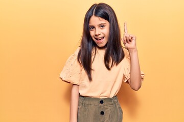 Beautiful child girl wearing casual clothes pointing finger up with successful idea. exited and...