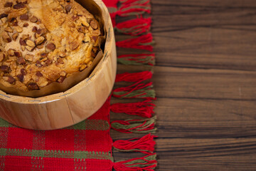 Fruit panettone covered with chestnuts on a cloth sideboard, on a table decorated for Christmas, with space for text.