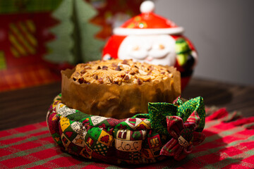 Fruit panettone covered with chestnuts, in a cloth basket on a green and red cloth sideboard and decoration for Christmas