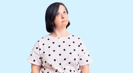 Brunette woman with down syndrome wearing casual clothes smiling looking to the side and staring away thinking.