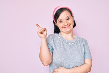 Obraz na płótnie Canvas Brunette woman with down syndrome wearing casual clothes smiling happy pointing with hand and finger to the side