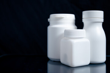 White medicine bottle on black background, medical concept.