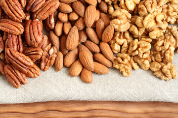 Raw peeled pecans, almonds and walnuts on a linen cloth. Closeup. Macro