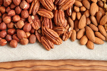 Raw peeled hazelnuts, pecans and almonds on a linen cloth. Closeup. Macro