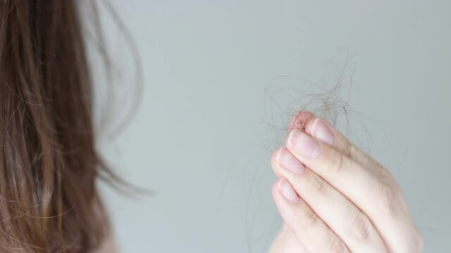 Girl holds a strand of hair front view, hair loss concept