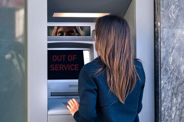 Woman can't withdraw cash money from credit card at bank machine. ATM is out of service, broken bank machine