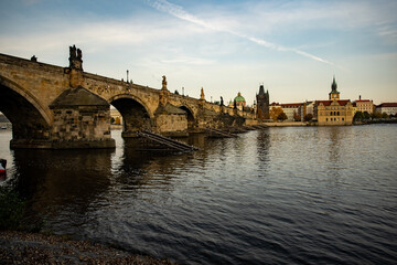 Fototapeta na wymiar view of the old stone bridge from the 14th century in the center of the city of prague on the flowing river Vltava river there are statues and the sky is blue at sunset in the Czech Republic