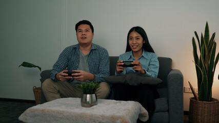 Asian couples are having fun playing games in their living room at night.
