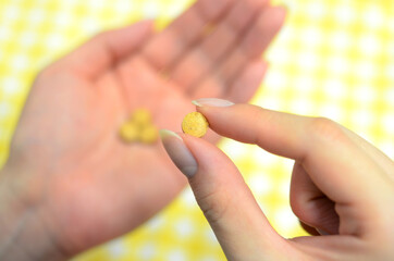 黄色い薬を持つ指先
