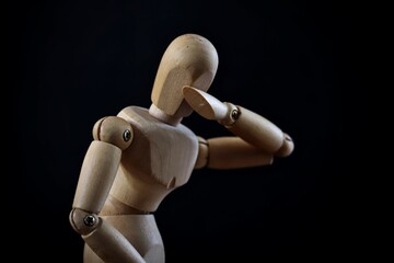 A portrait of a wooden mannequin showing emotion like sadness, loneliness, fear and depression on black background.