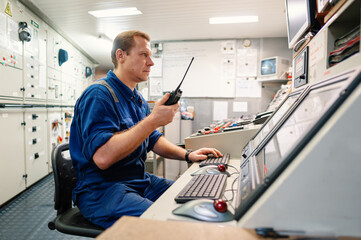 Marine engineer officer controlling vessel engines and propulsion in engine control room ECR. Ship...