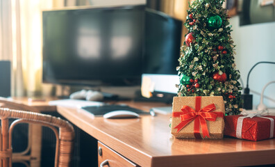 Christmas tree and wapped present boxing decorated at home office with laptop computer.