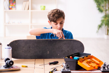 Boy reparing skateboard at home