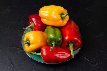 Bright juicy fresh sweet bell peppers of red, yellow and green color on a black background. Still life food