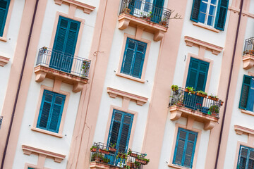 Building exterior with windows and balconies in Sicily, Italy.