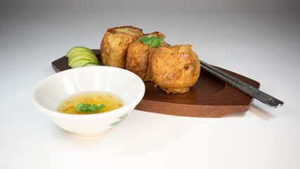 Hoi jo, Deep Fried Crab Meat Rolls, chinese traditional food on the wooden plate, serve with side dishes cucumber & plum sauce.
