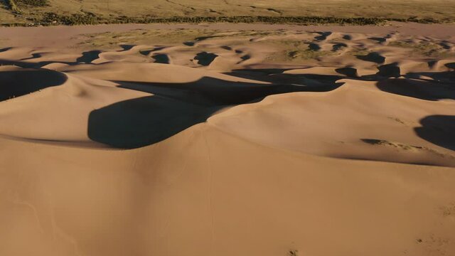Aerial view around a person standing on a sandbank, during sunset, in The great sand dunes national park, Colorado, USA - orbit, drone shot