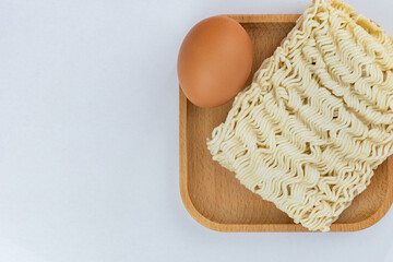 One Dried instant noodles and egg on wooden plate