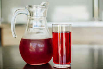 Cherry juice in a glass and in a glass teapot. A jug with a red drink. Berry fruit drink. Transparent glass