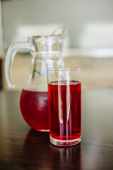 Fototapeta na wymiar Cherry juice in a glass and in a glass teapot. A jug with a red drink. Berry fruit drink. Transparent glass