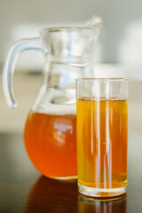 Apple juice in a glass and in a glass teapot. A jug with a yellow beverage drink. Sea buckthorn fruit drink. Clear glass