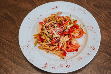 Spicy salad with cucumbers and tomatoes, bell pepper and sesame seeds. Diet food. On a white plate. Dish on a dark background.