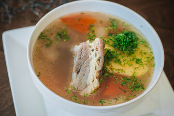 Diet soup with a small piece of pork and potatoes. Lean broth. Nutrition for gastritis. White bowl on a dark background
